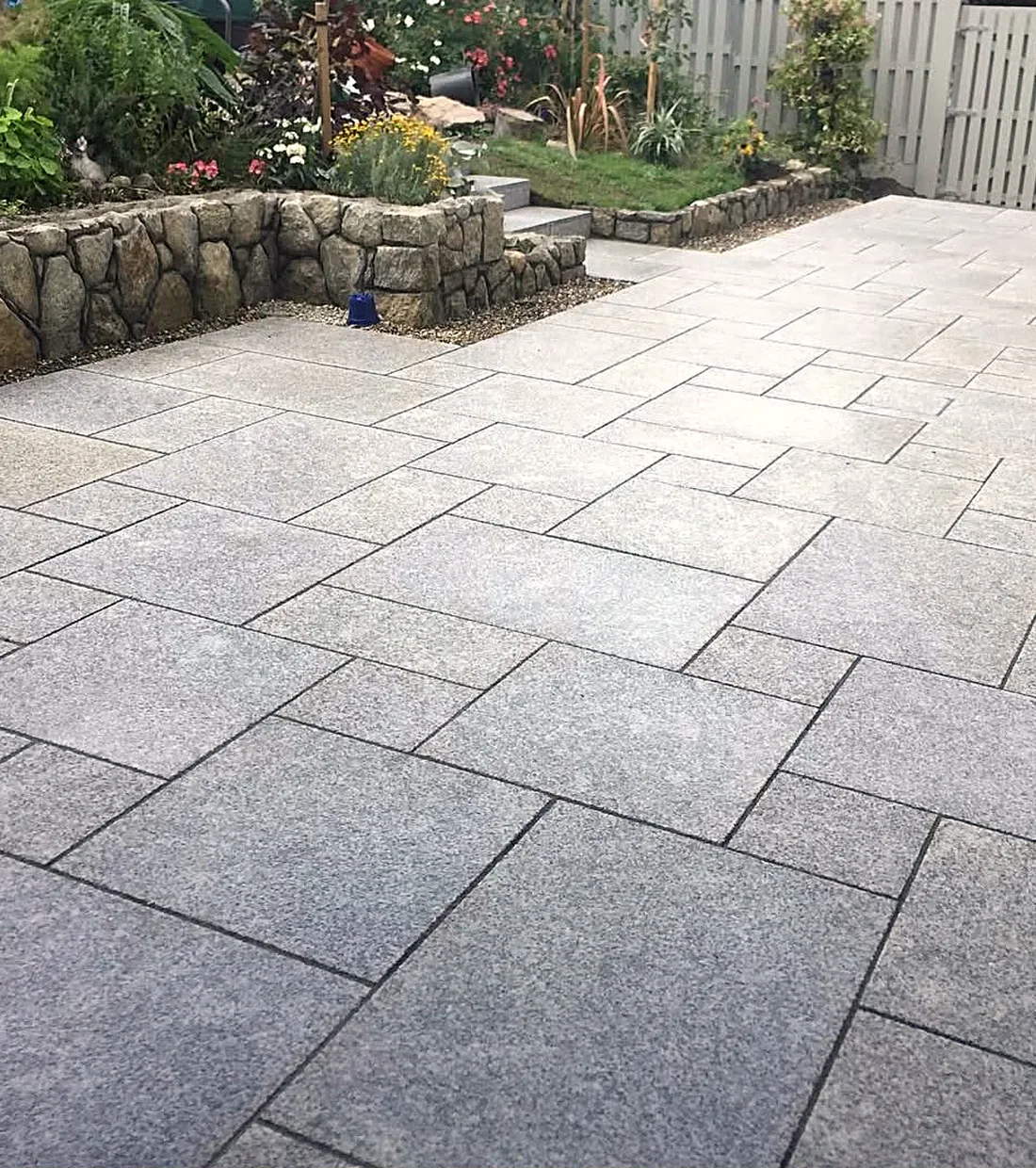 Granite paving with a stone wall and lawn