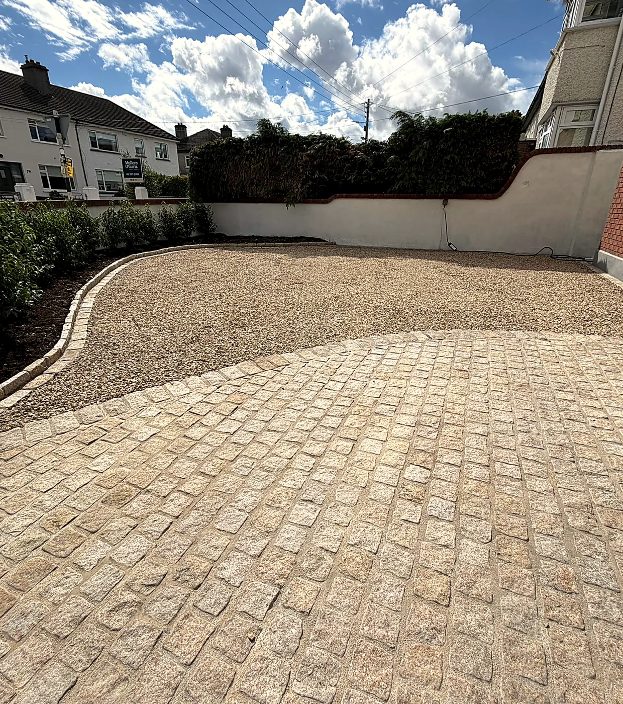 Finished gravel driveway in Churchtown with a granite cobble apron and a curved cobble edge along a planted bed