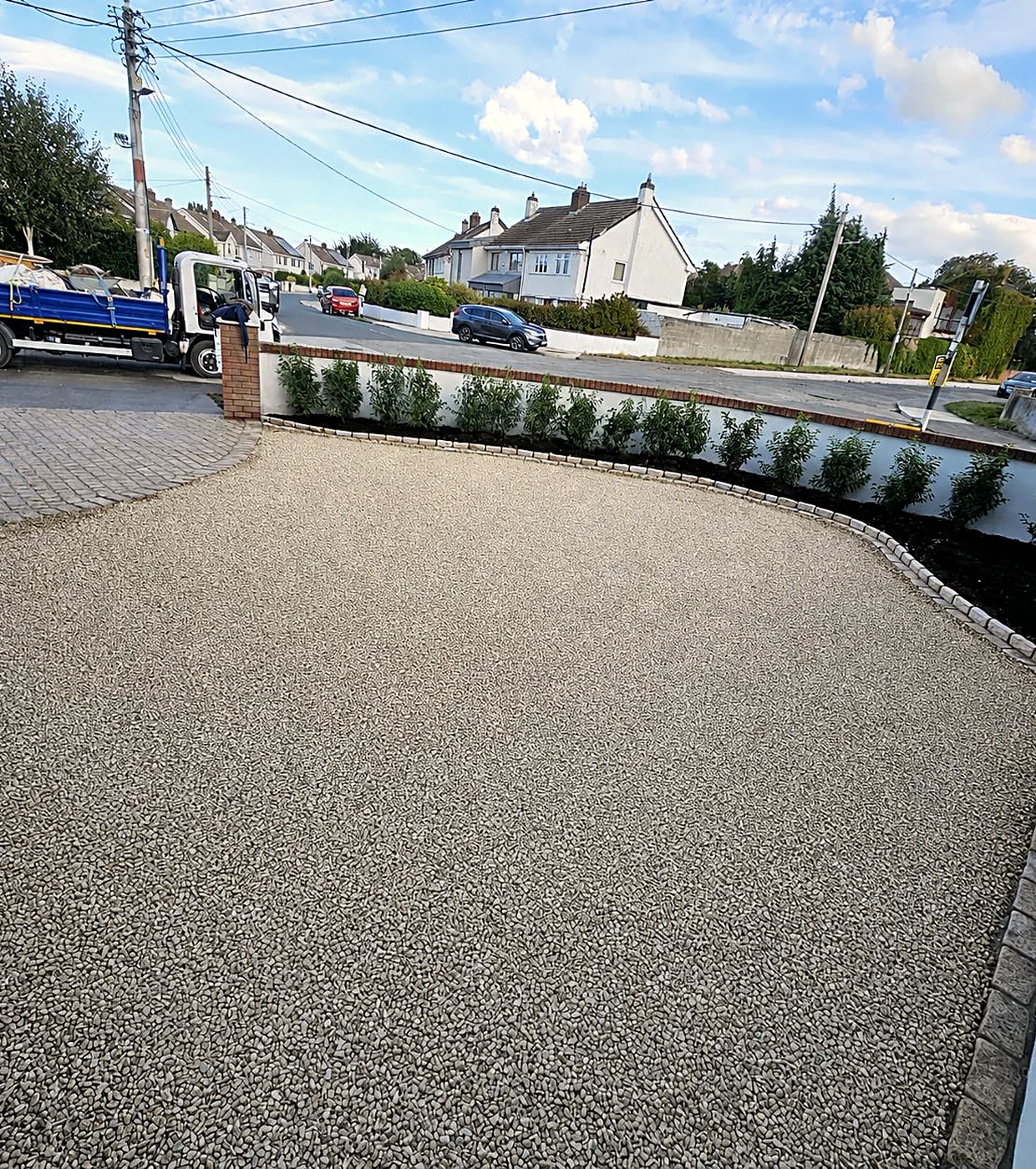 The Churchtown gravel driveway from the gate, the gravel held by a cobble edge inside the rendered boundary wall