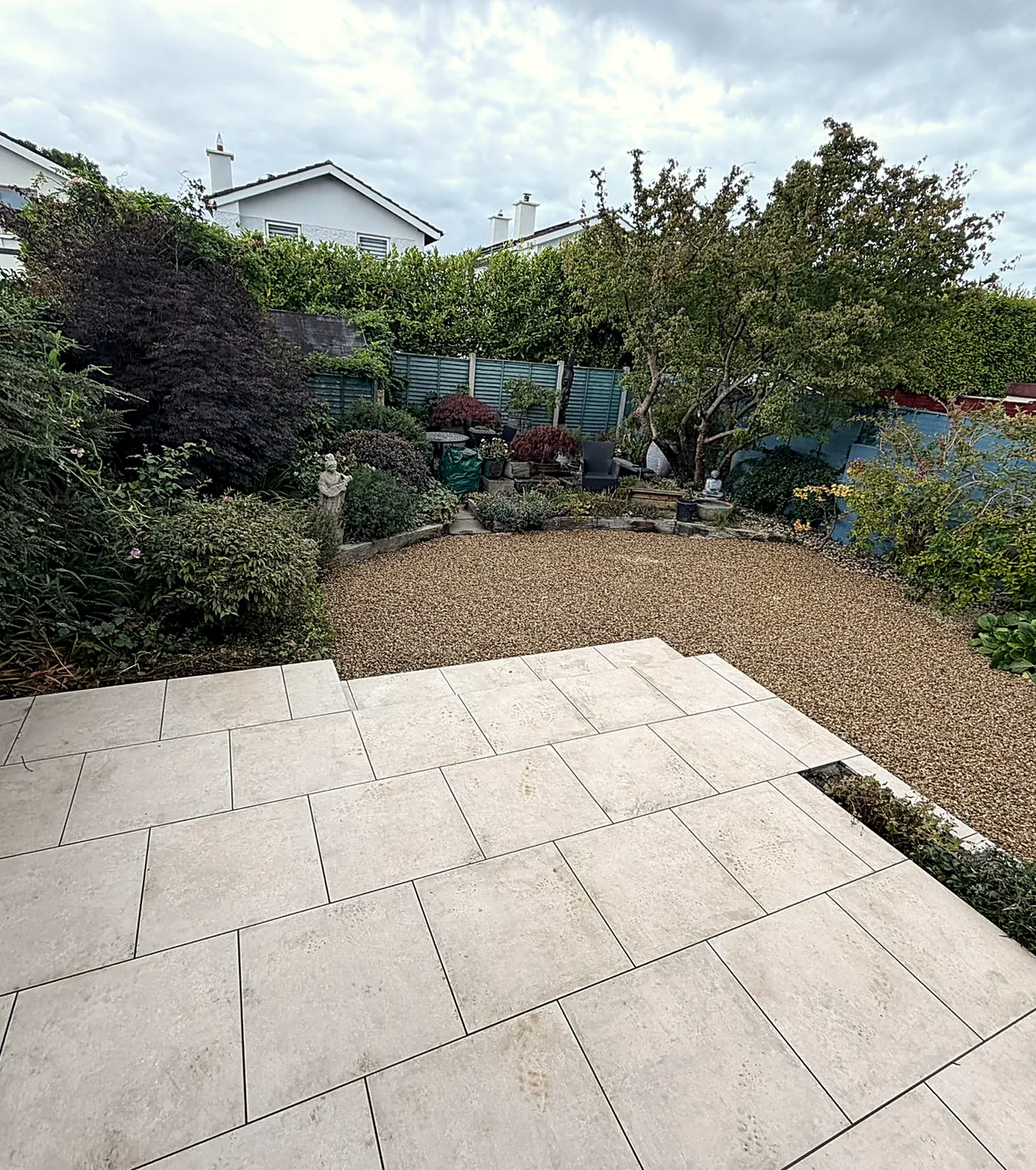 Looking down the Stillorgan garden from the porcelain patio, over the step to the gravel bed, the shrubs and the fence at the end