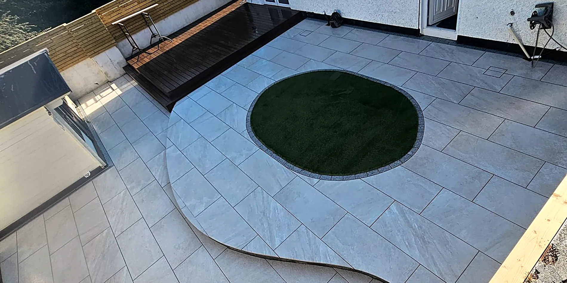 Large-format porcelain patio with curved lawn inset
