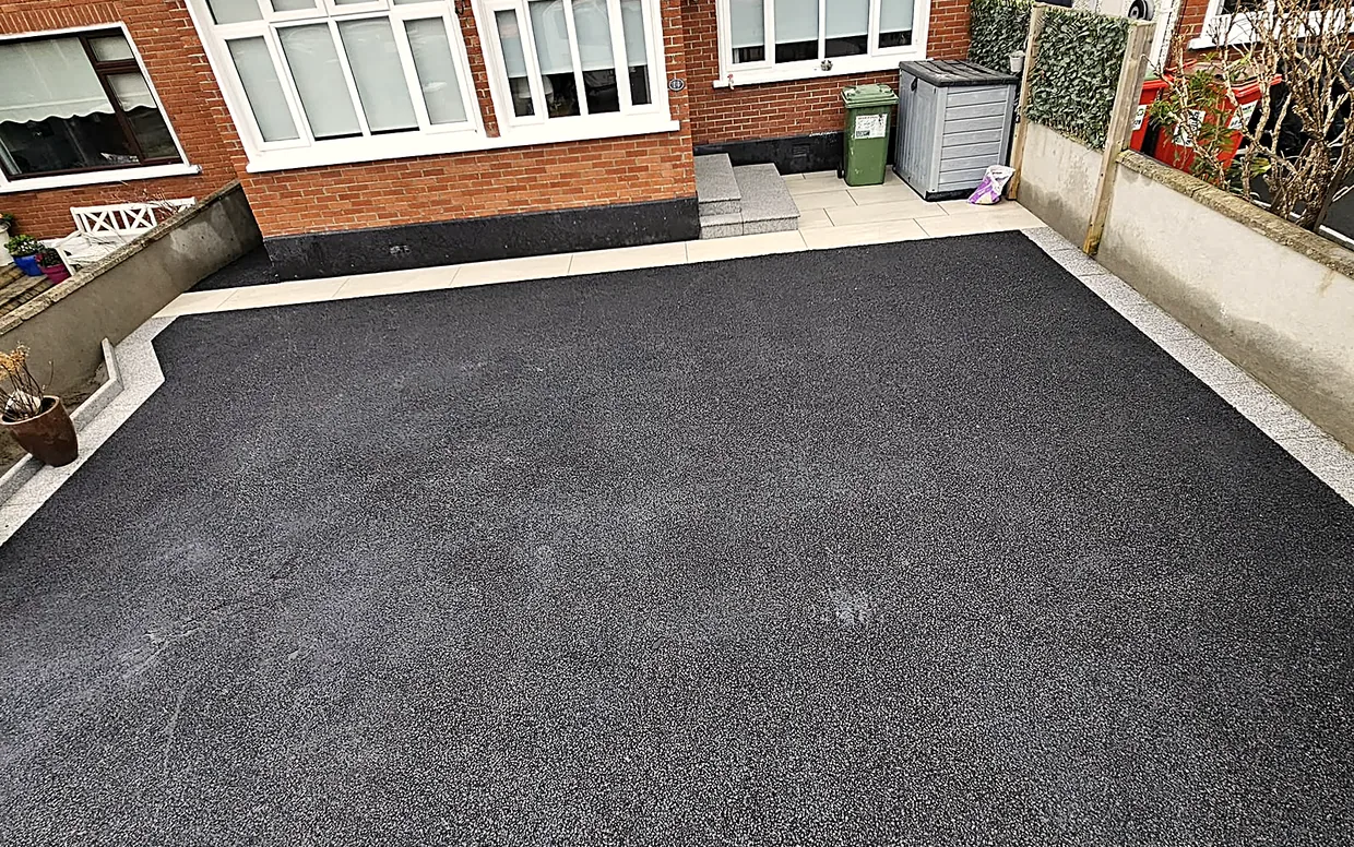 A finished tarmac driveway in South Dublin, laid to falls with a silver granite edge, a porcelain path and a granite step at the door.
