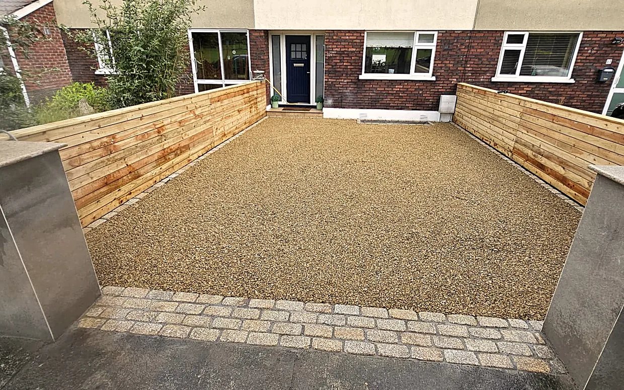 A gravel driveway framed by a cobble border, finished against the house.