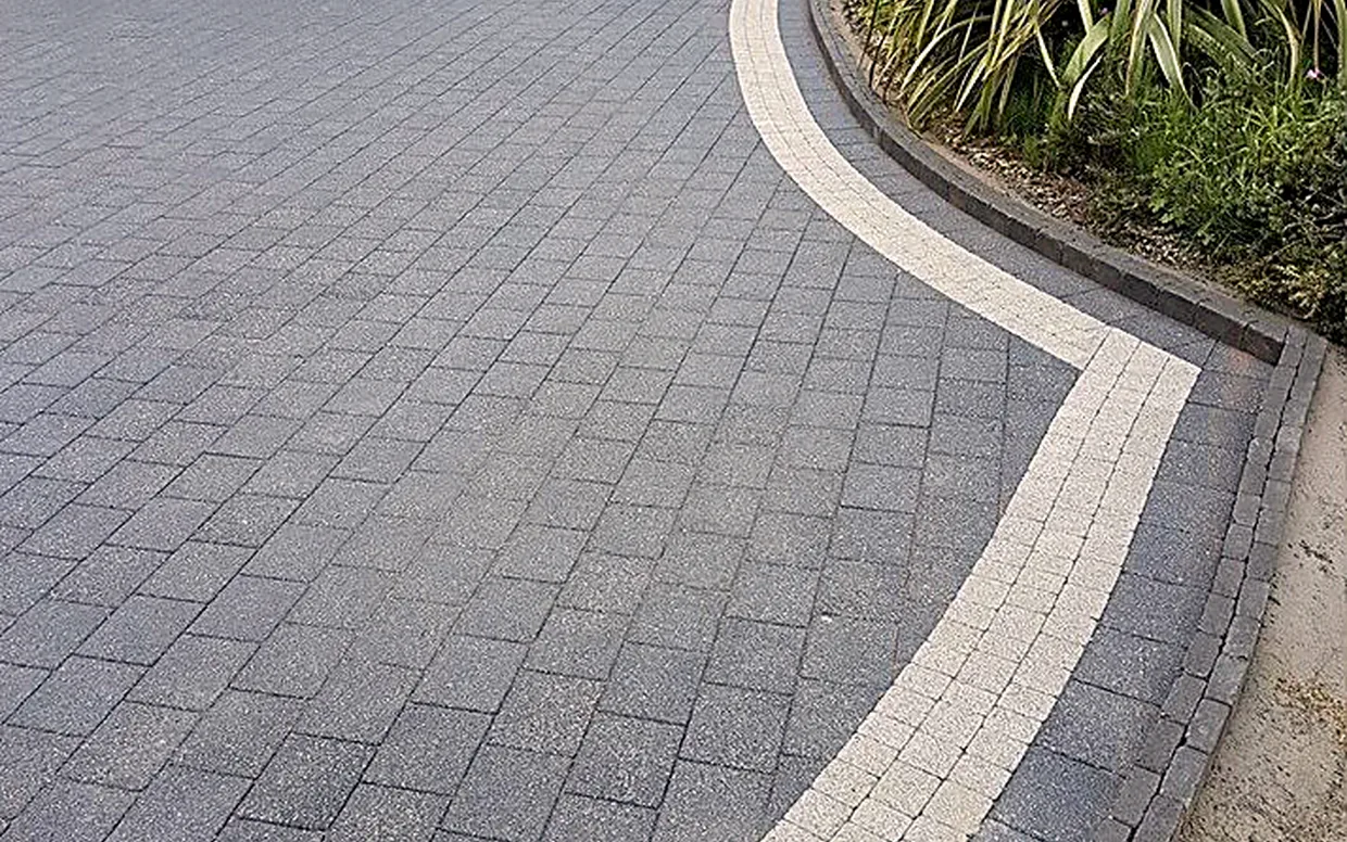 Charcoal block paving with a sweeping silver-grey border, showing how colour and pattern change the look.