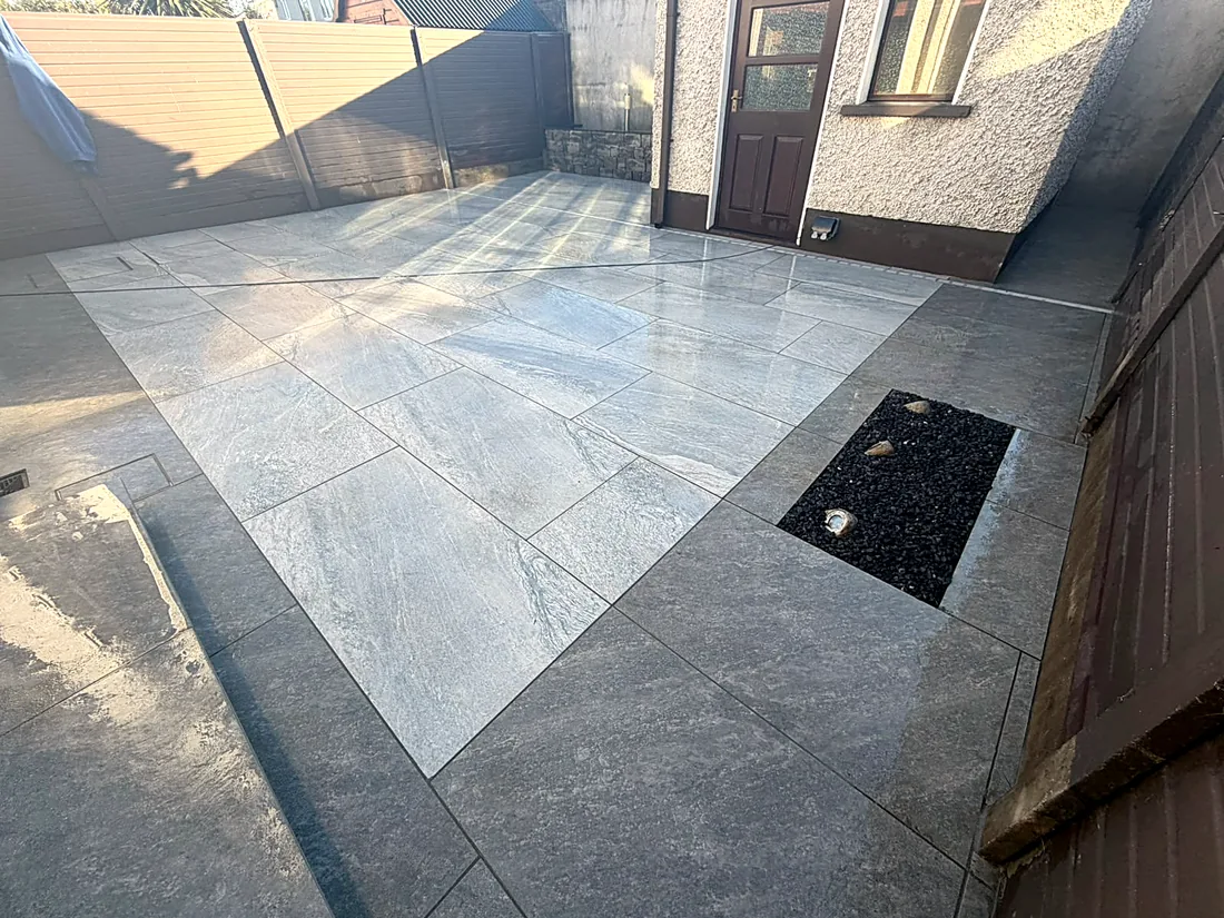 The porcelain patio behind the house, running to the back door, with a gravel strip along the house wall