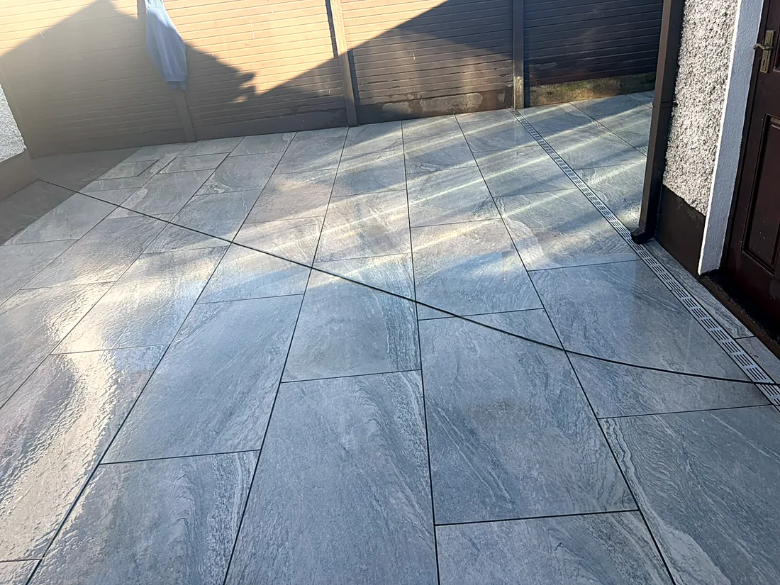The porcelain patio on the fence side of the back garden in the sun