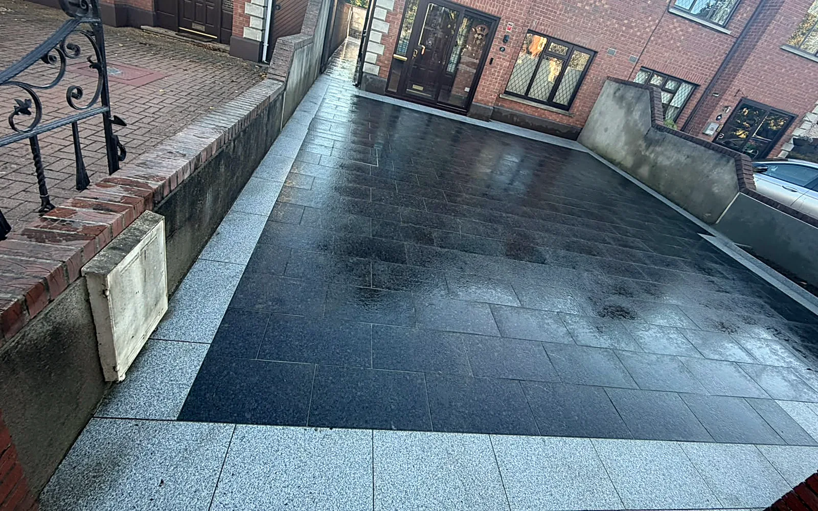 The new black granite driveway in Cabinteely from the gate, the silver granite border wrapping the raised bed - after