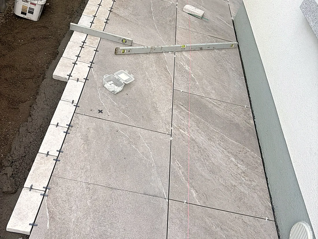 Mid-work: the porcelain paving going down along the house, the edge set to a line
