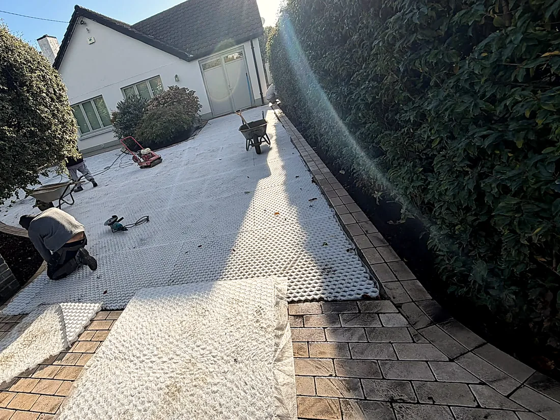 Mid-work: the gravel grid laid across the drive, a worker kneeling at the apron