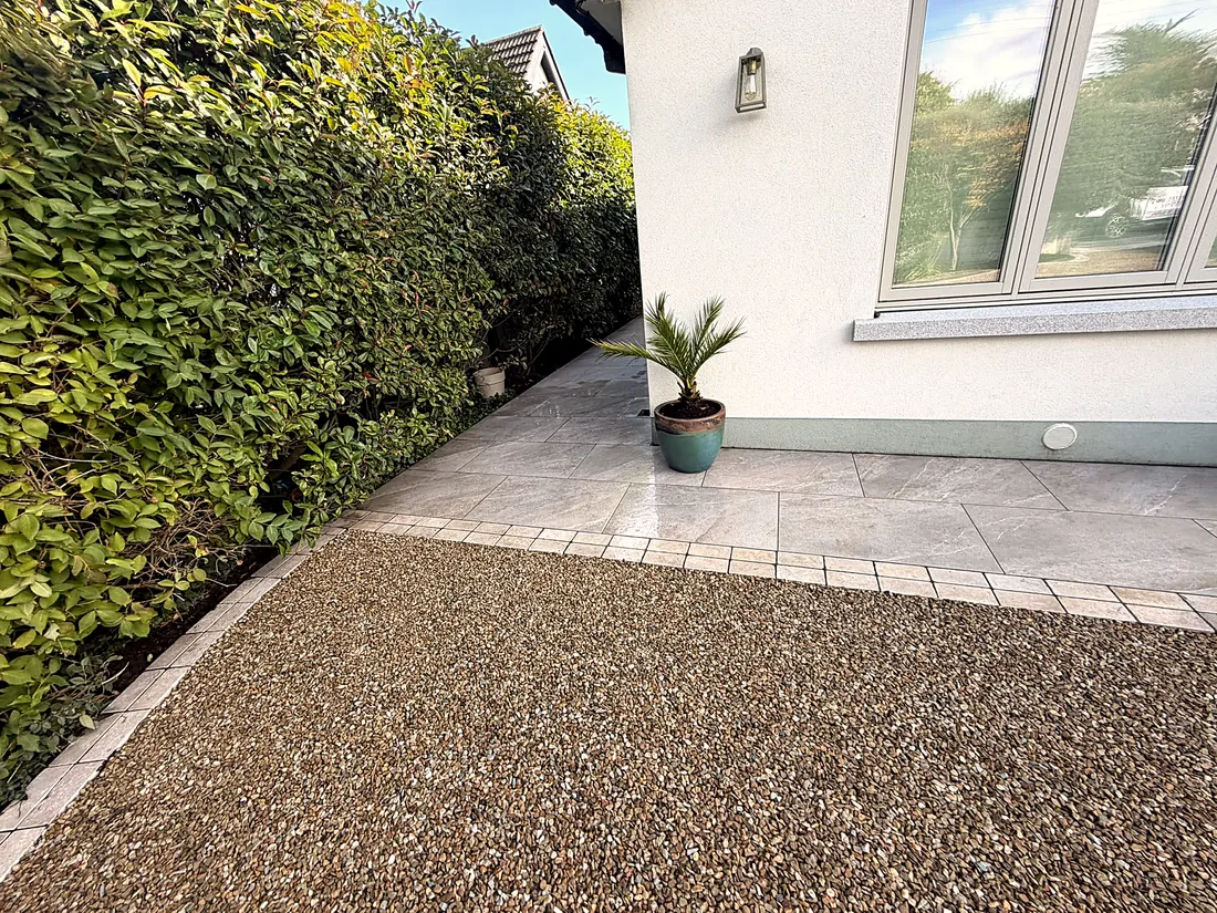 Golden gravel up to the porcelain paving and the hedge at the side of the house