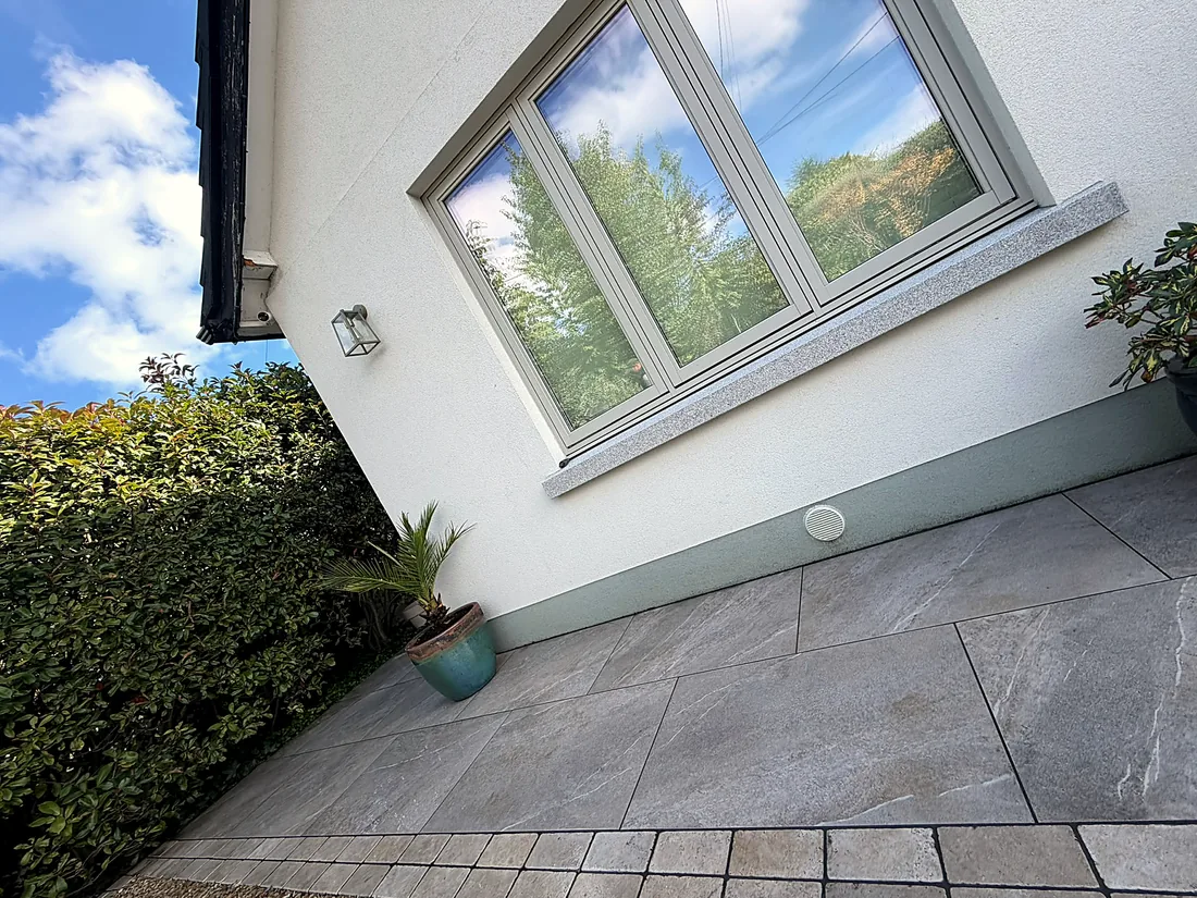 The porcelain paving at the house wall with its limestone cobble border