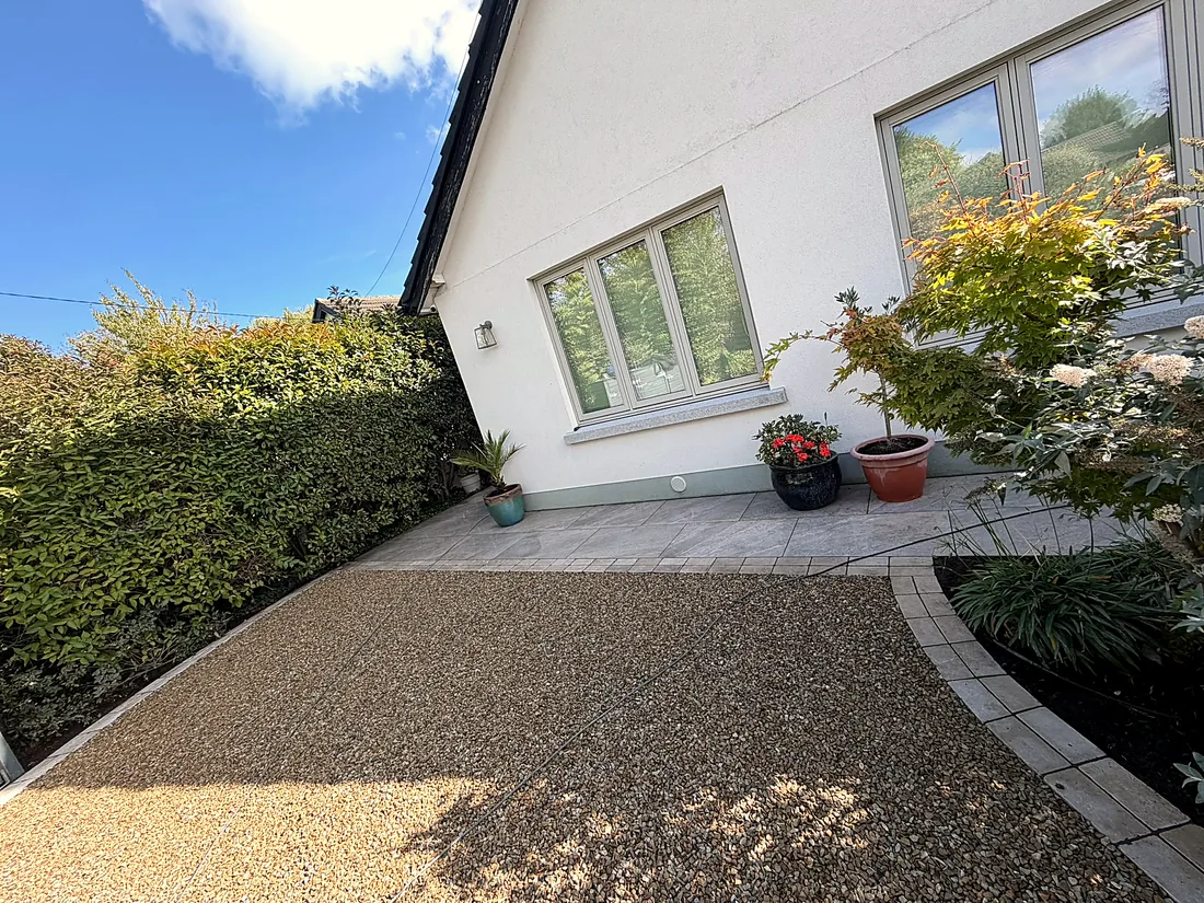 The gravel drive meeting the cobble border and the porcelain path, pots under the window