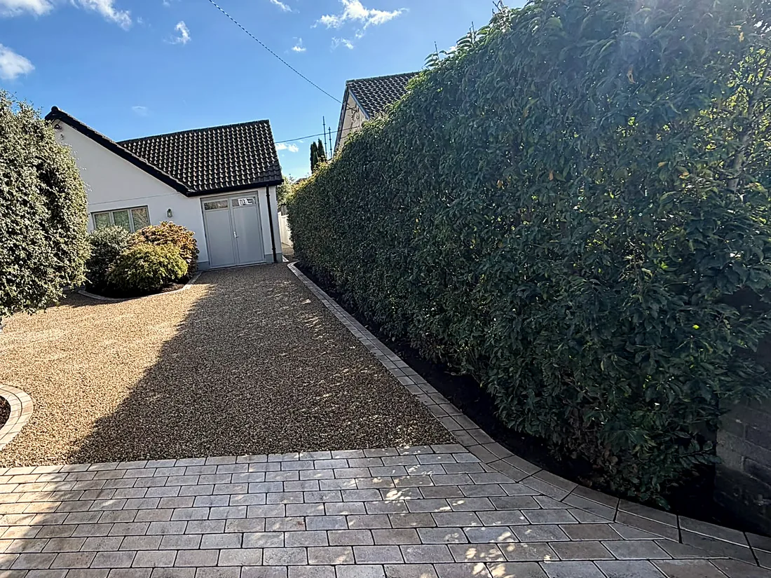 The finished drive from the gate: the cobble apron, the gravel and the planting by the hedge