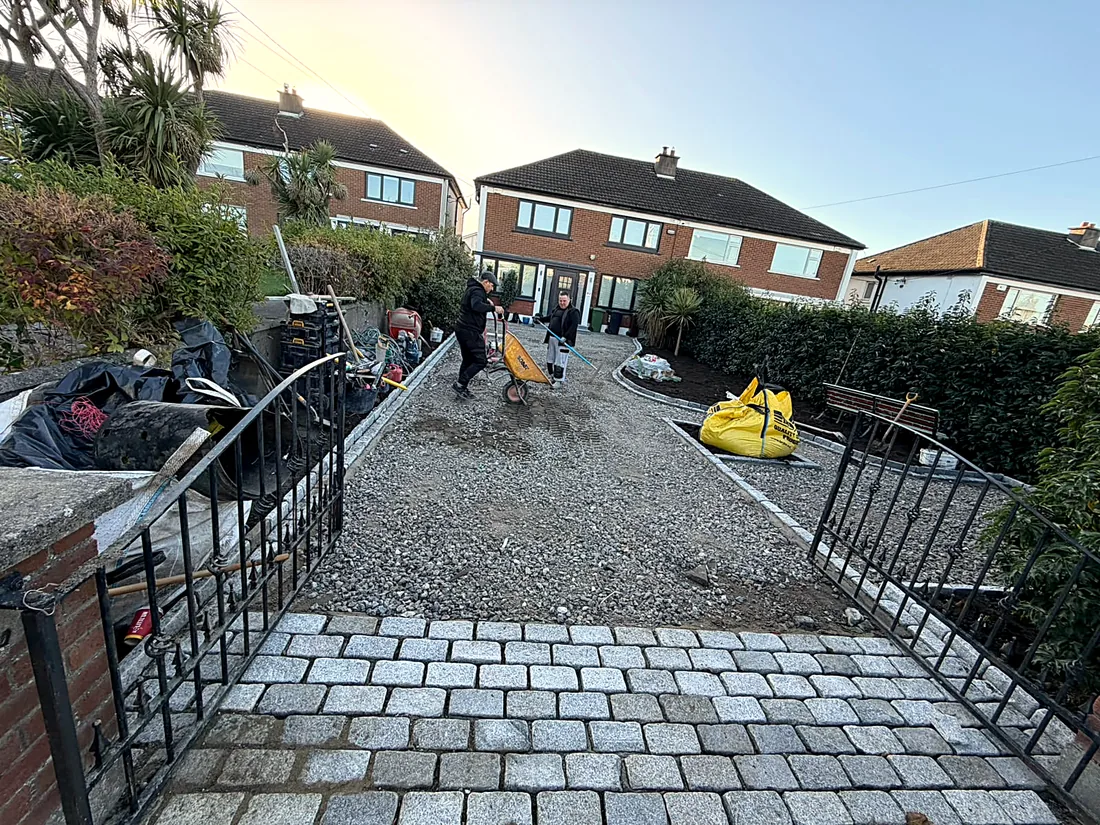 The gravel being spread and raked between the new granite edges