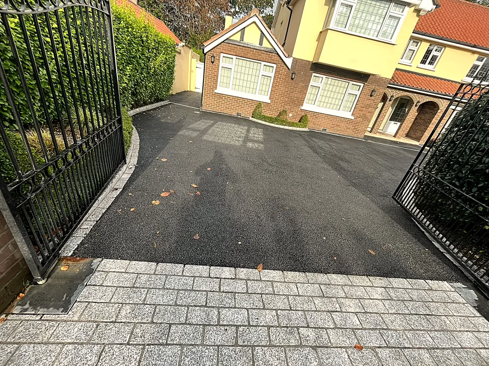 Tarmac driveway with granite cobble apron behind gates