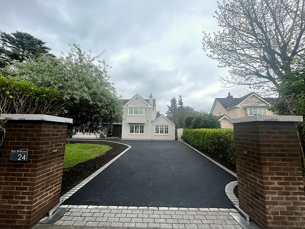 Tarmac driveway with brick pillars and granite border