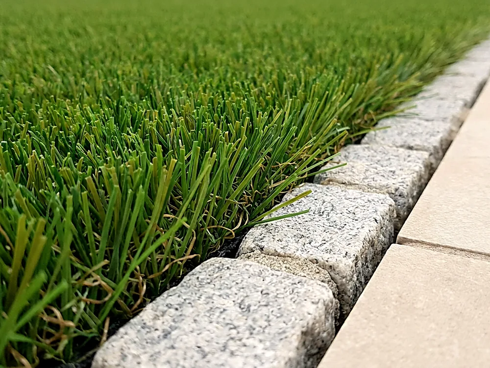 Close detail of artificial grass and a paved edge